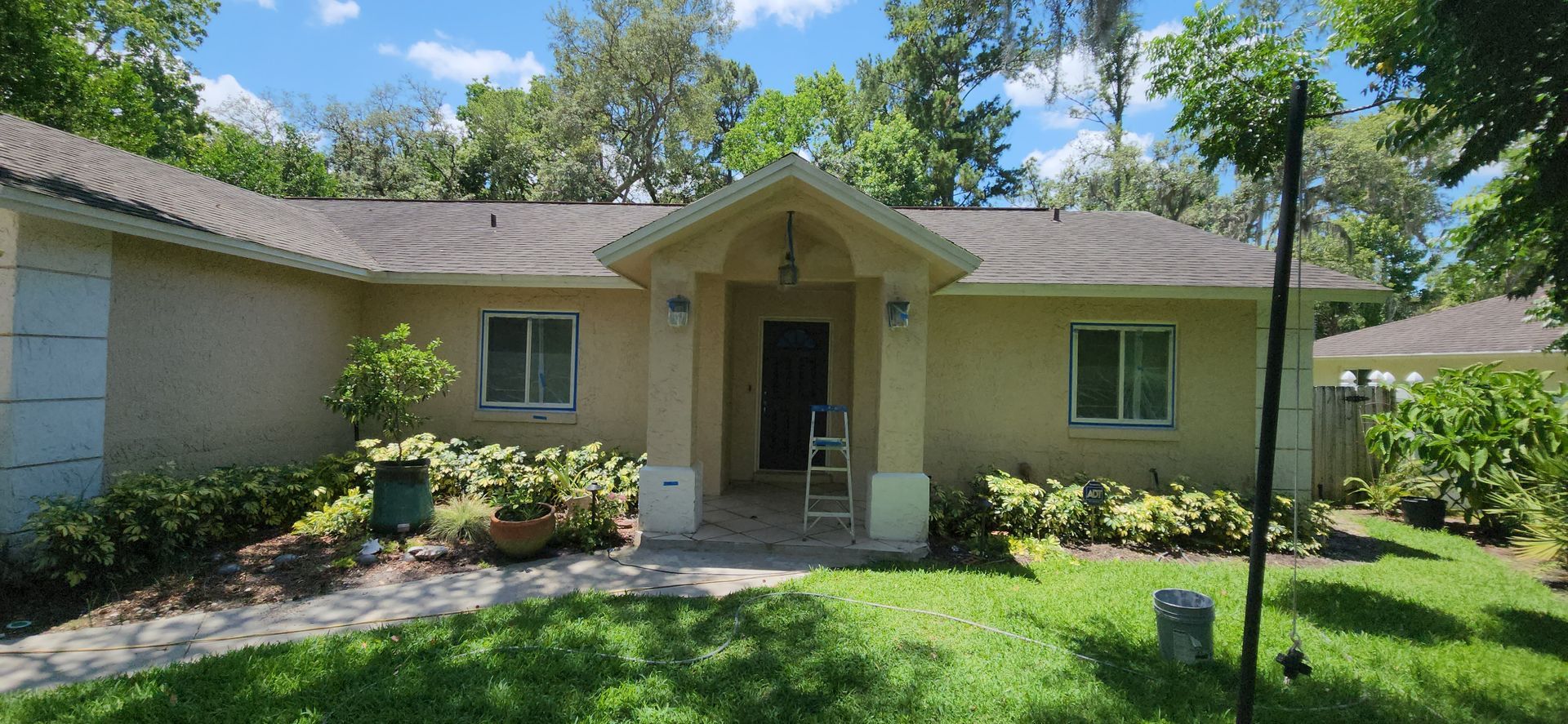 The backyard of a house with a covered patio and a large lawn.