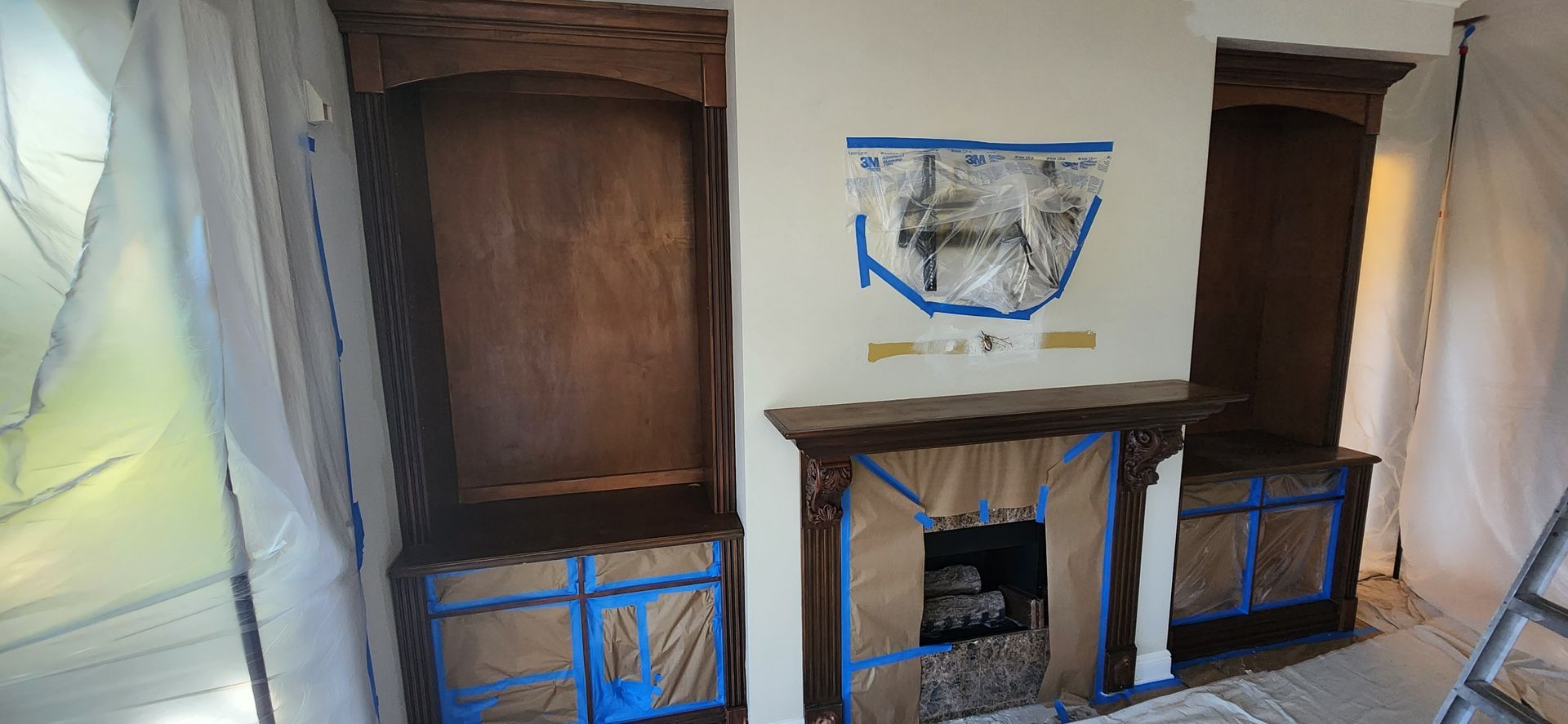 The backyard of a house with a covered patio and a large lawn.