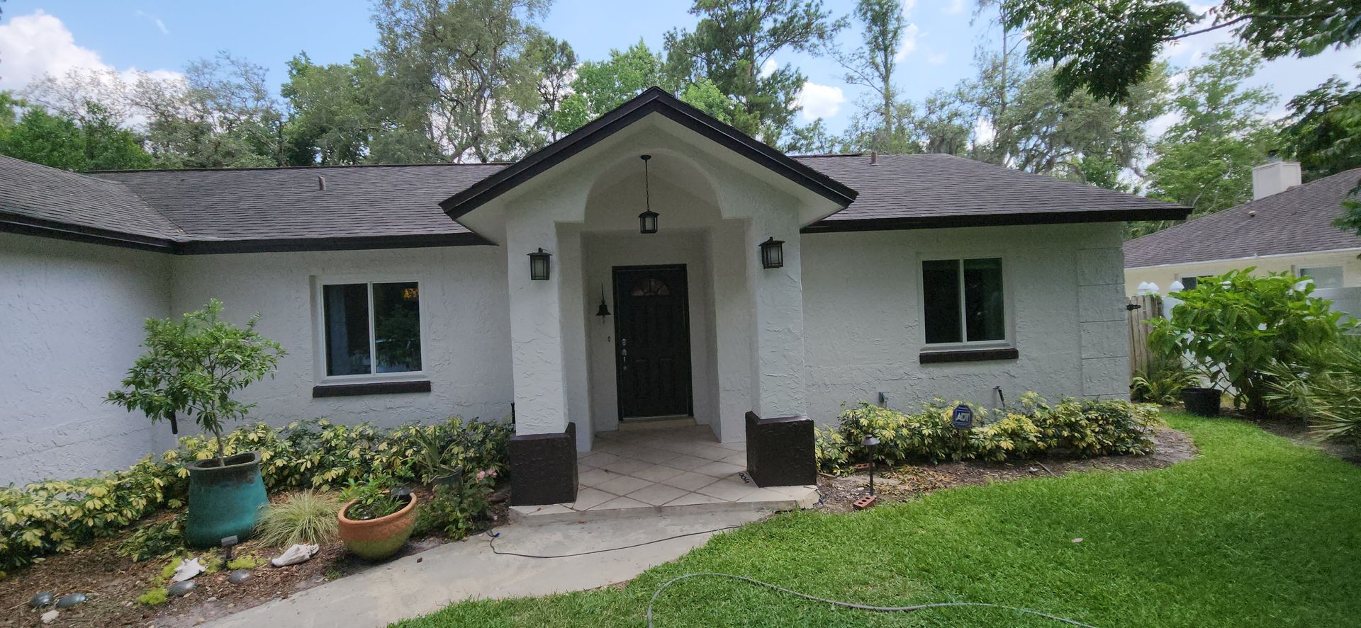 The back of a house with a covered porch and a white fence.
