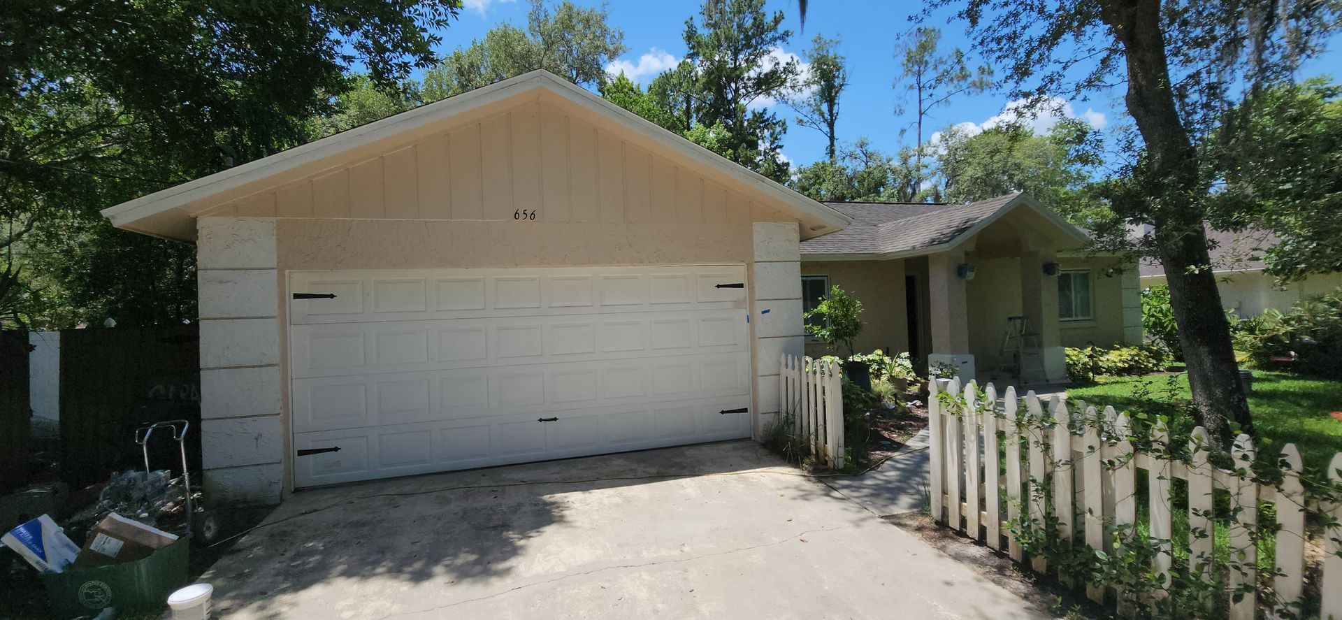 The backyard of a house with a covered patio and a large lawn.