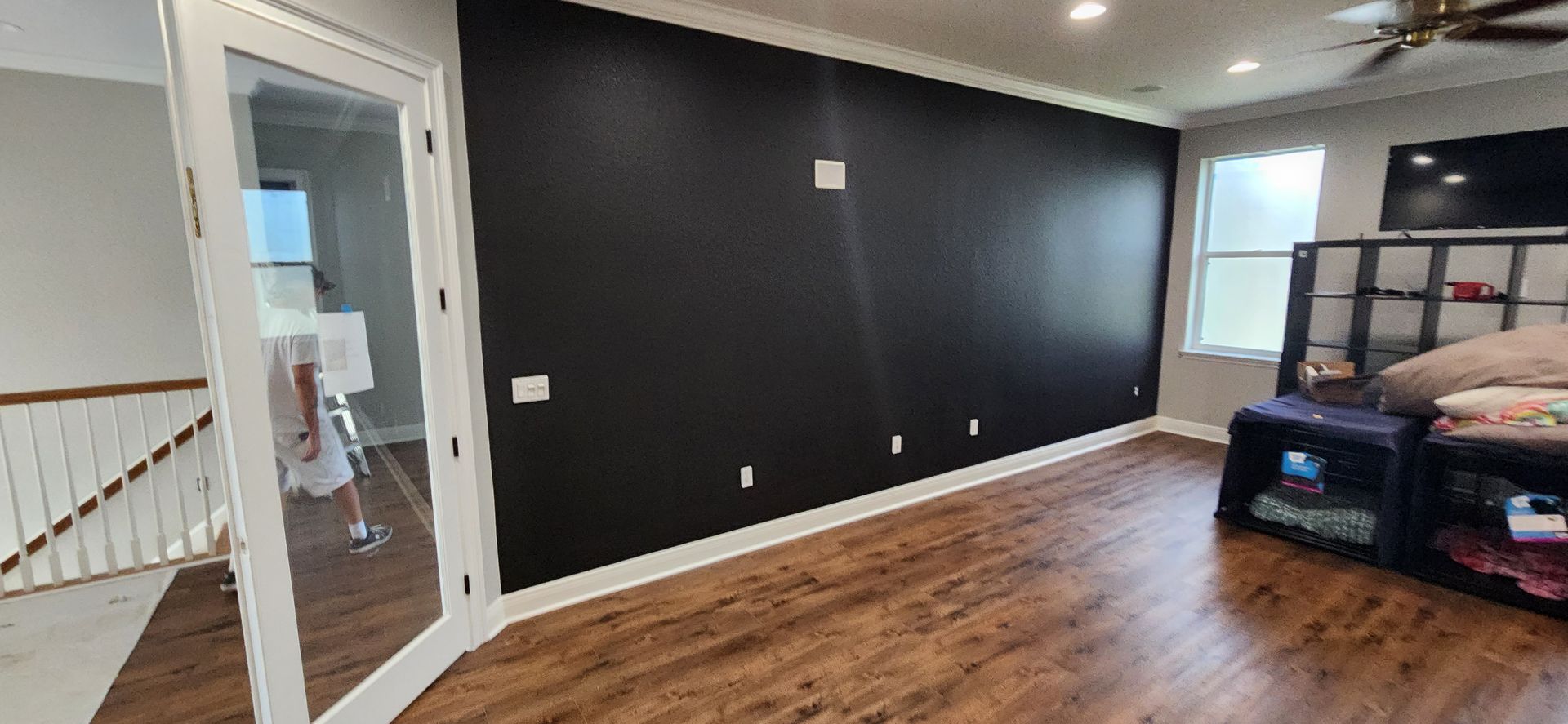 The back of a house with a covered porch and a white fence.