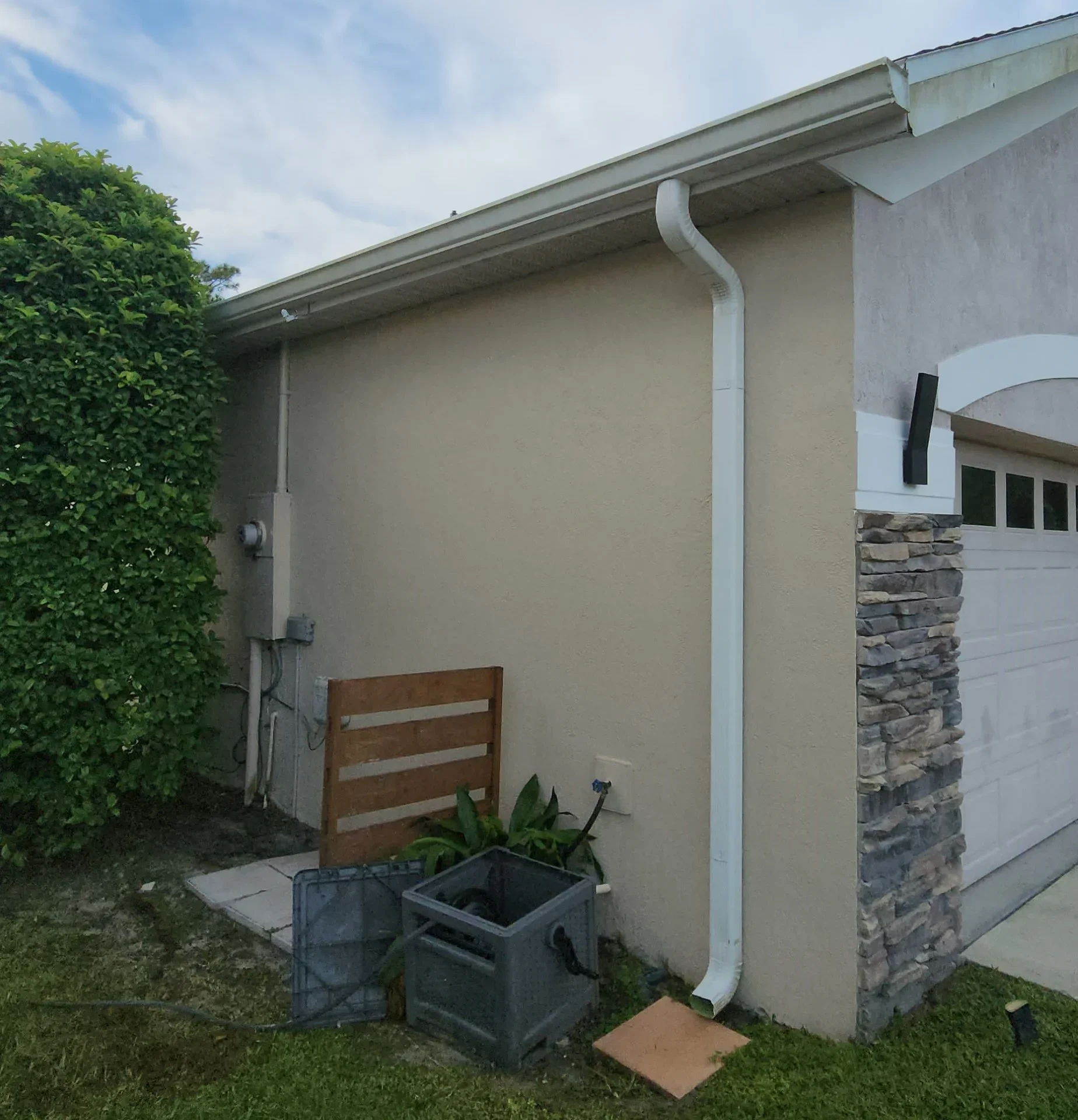 Stucco exterior wall with white trim and stone veneer accent before painting