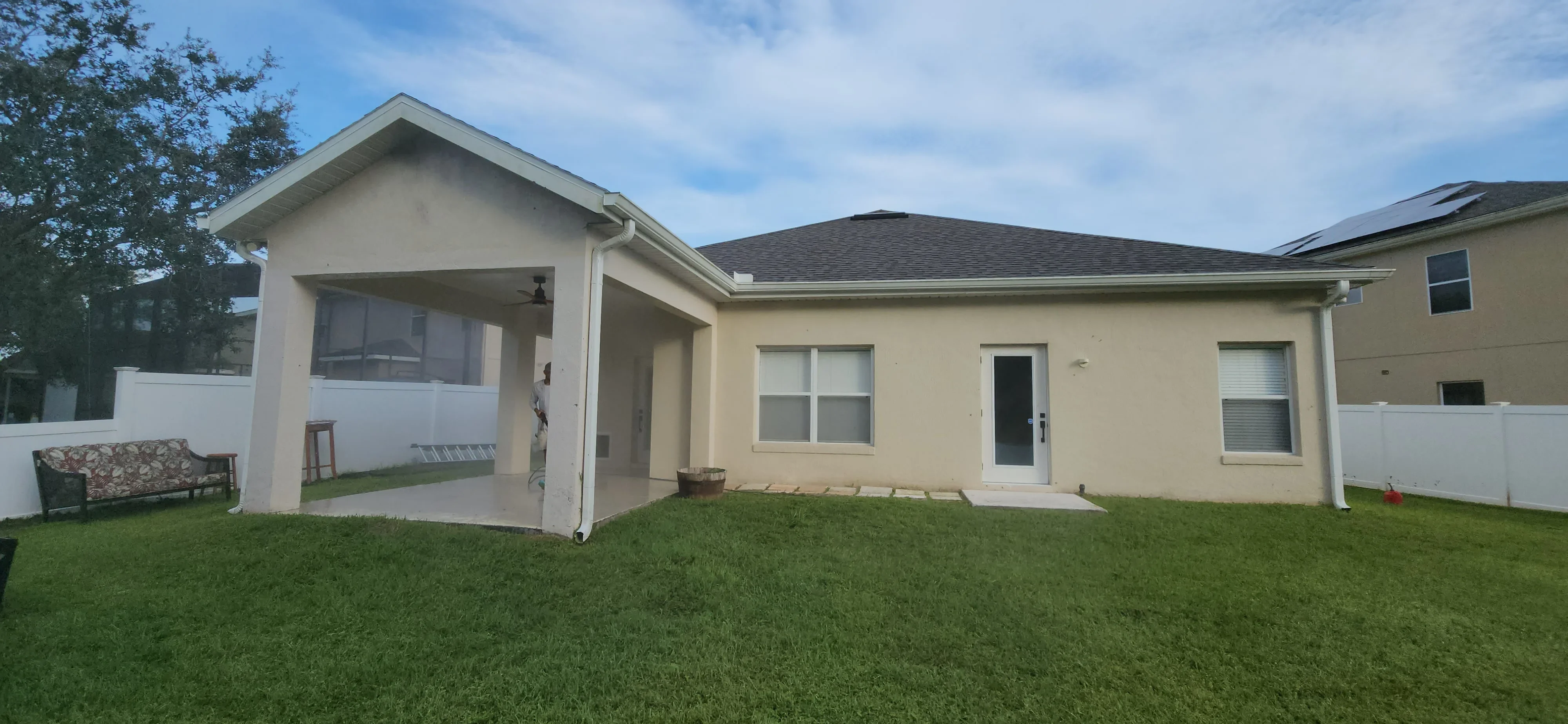 Cream-colored stucco house with painted patio cover and trim, manicured lawn
