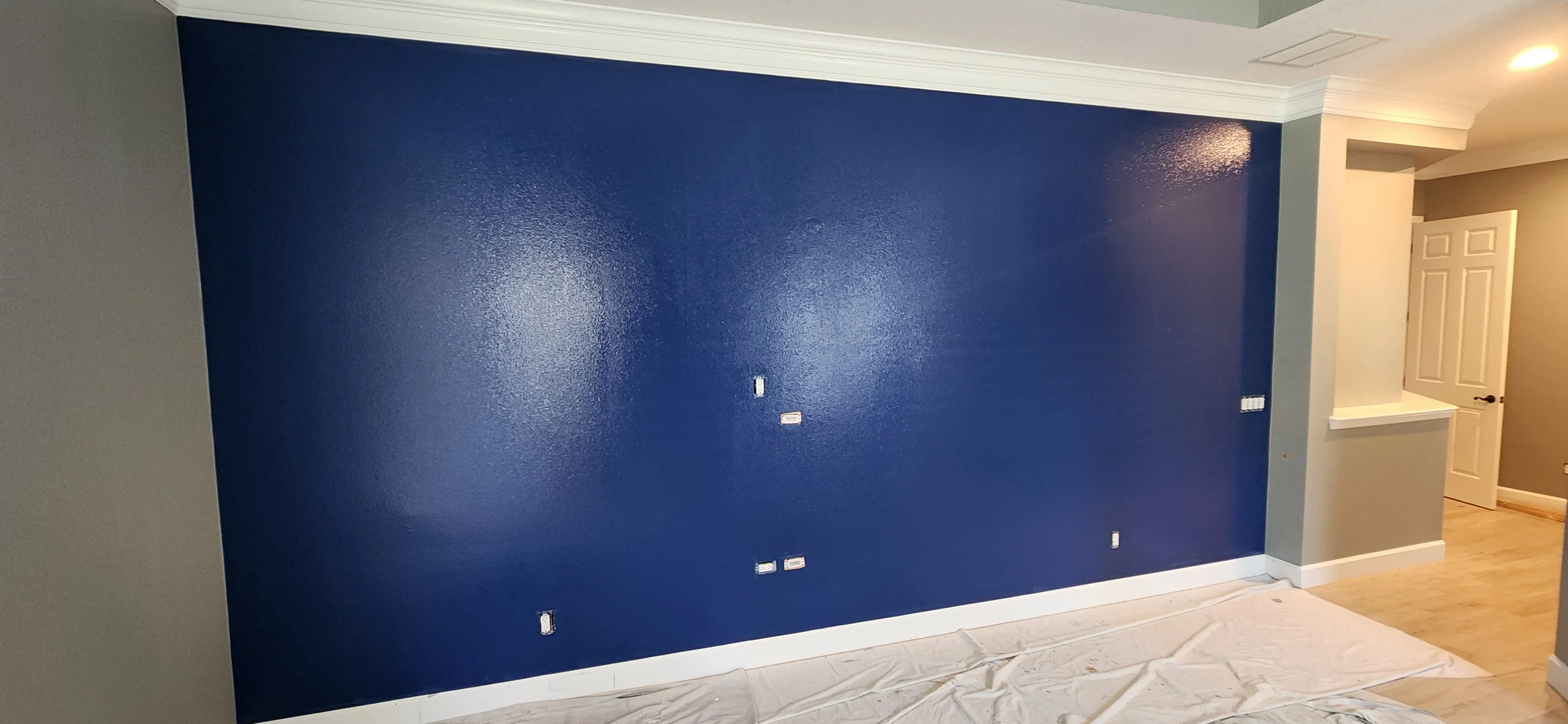 Navy blue painted accent wall with white trim and electrical outlets in bedroom