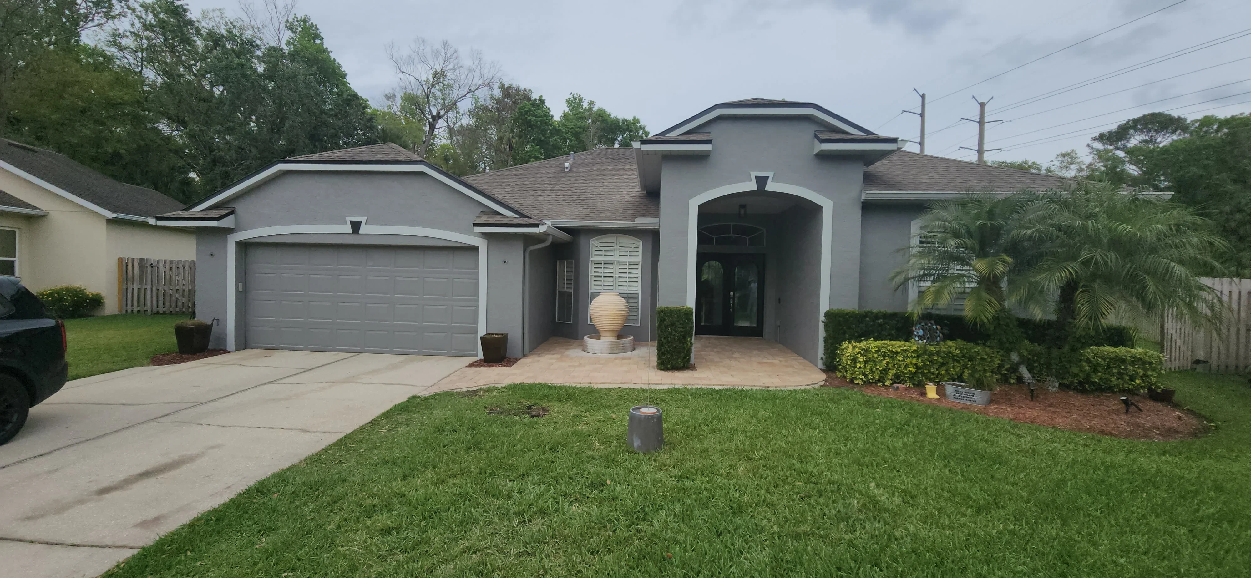 Gray stucco house exterior with white trim, painted garage door, and landscaped front yard