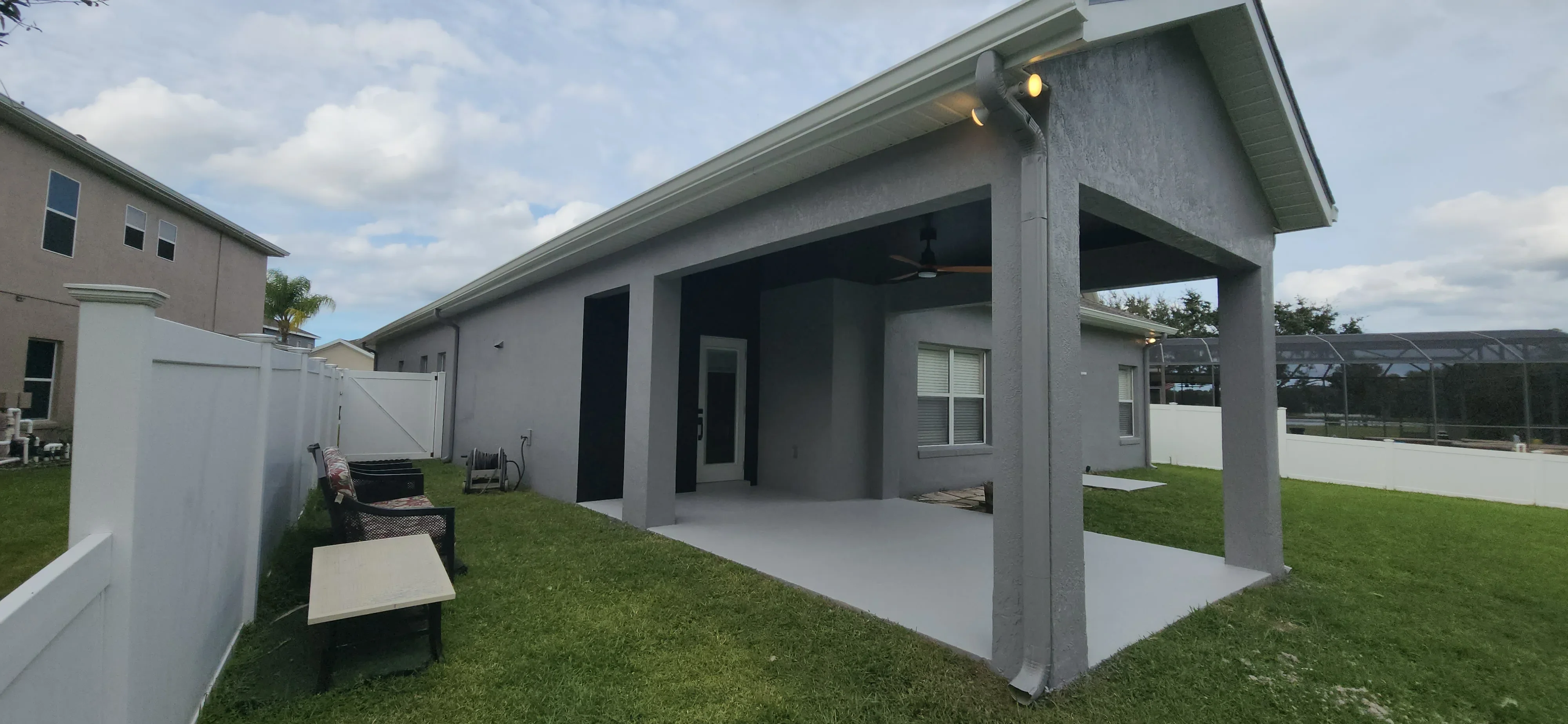 Gray stucco house exterior with white trim, painted patio cover, and finished soffit