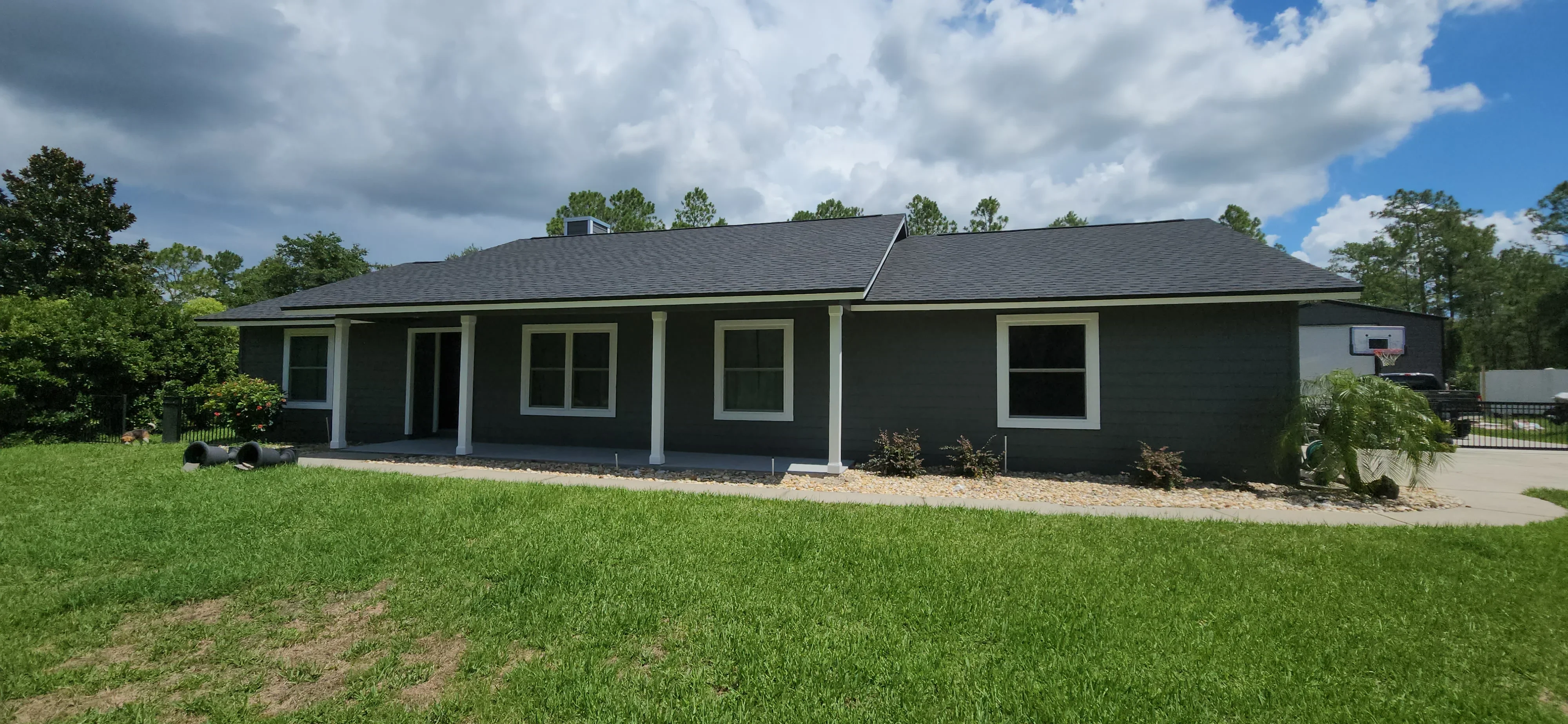 Dark green painted house exterior with white trim, columns, and window frames