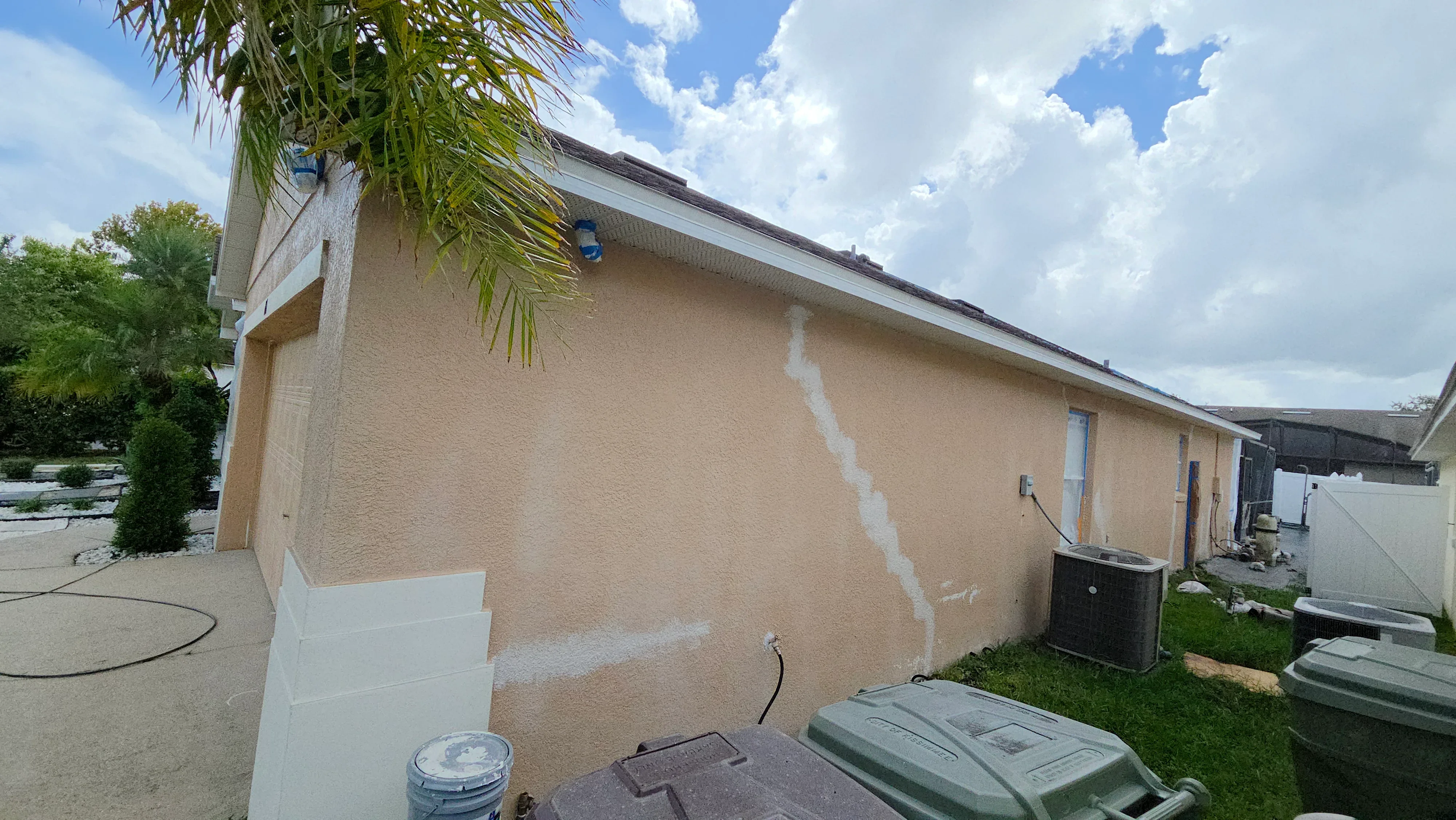 Stucco exterior wall with primer and masking tape applied to textured surface