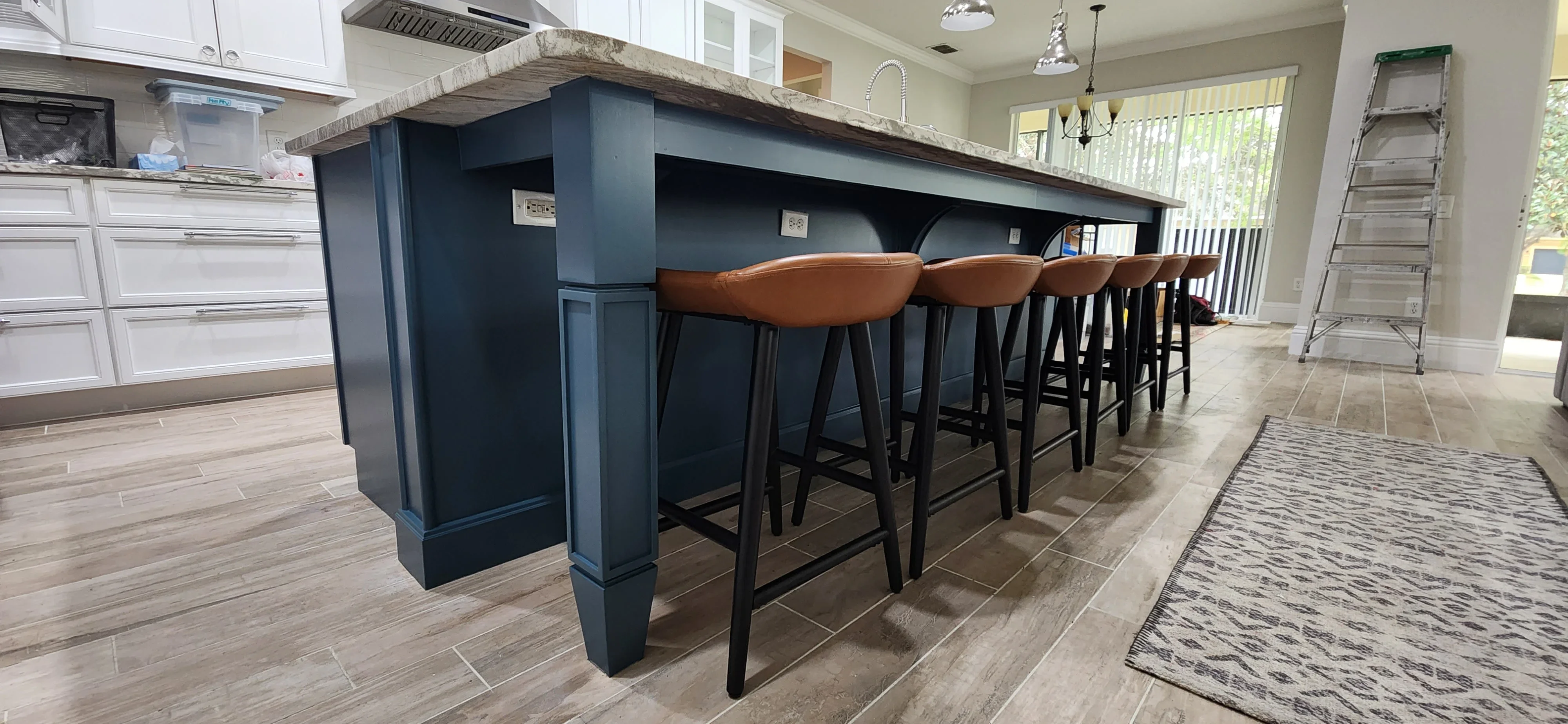 Dark blue painted kitchen island with wood countertop and brown leather bar stools
