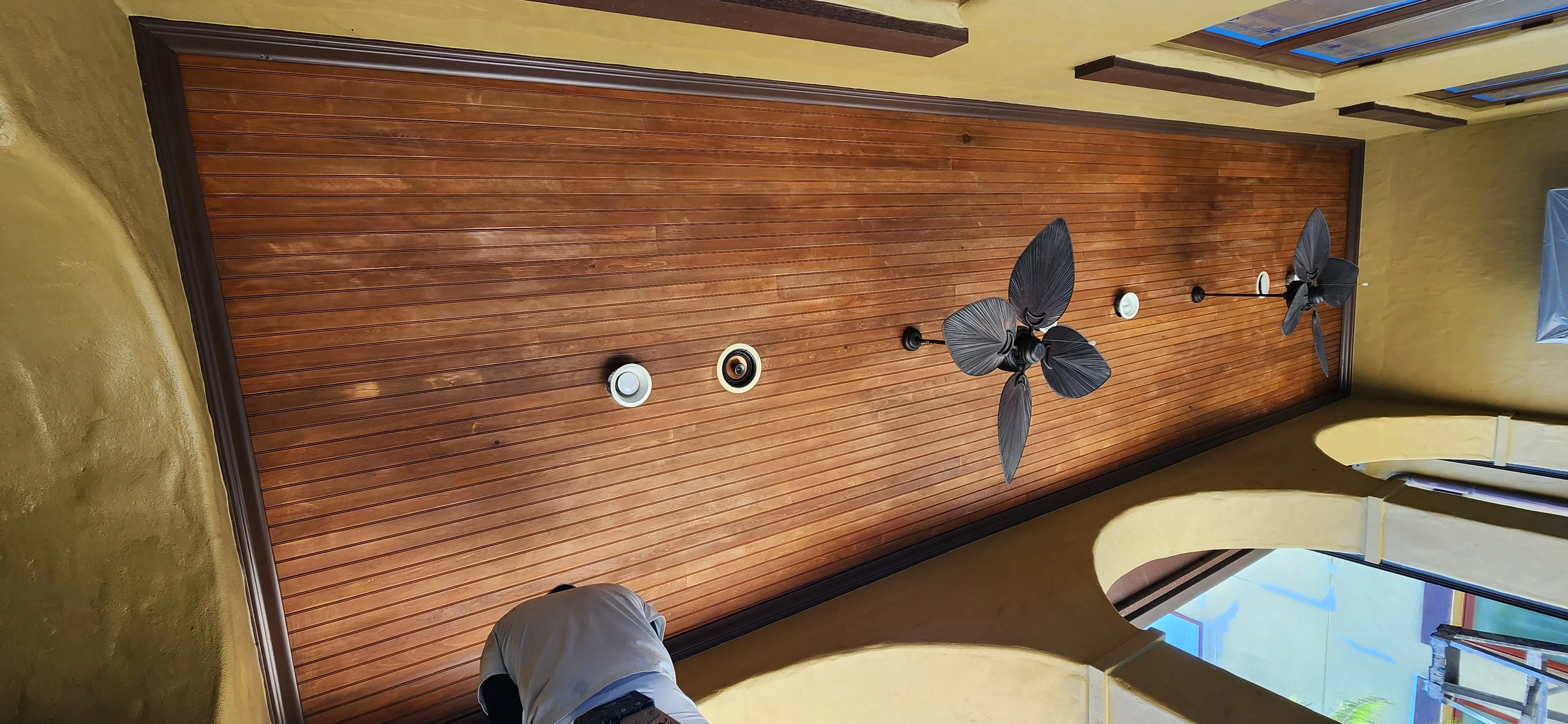 Horizontal wood plank accent wall with recessed lights and black propeller wall art