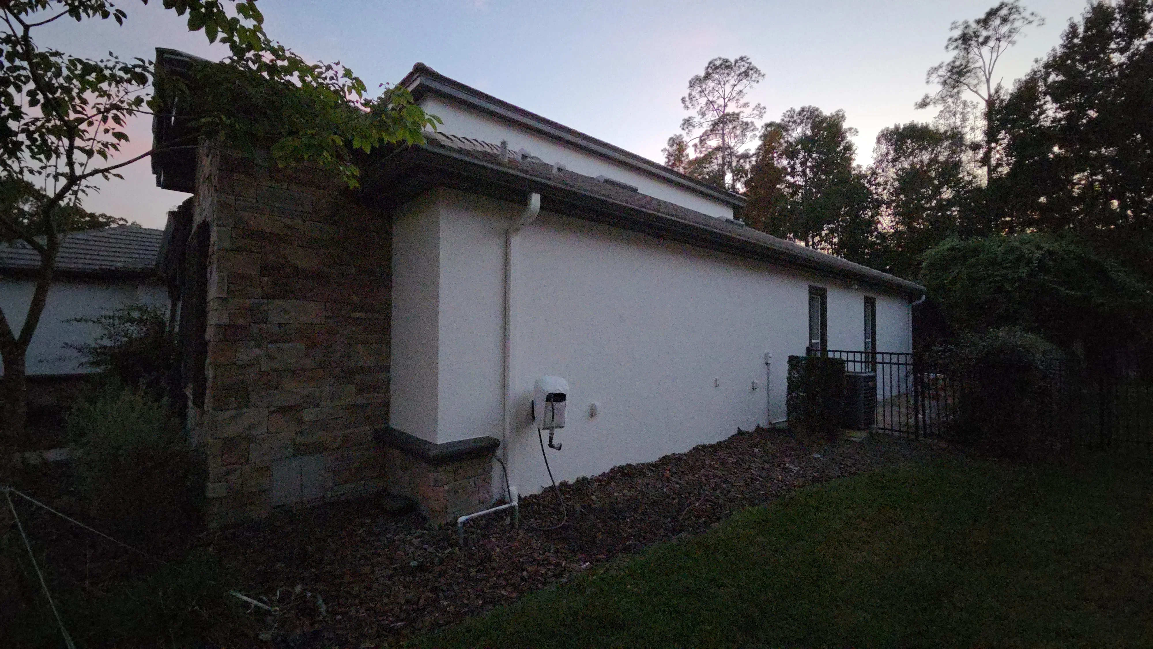 White painted exterior wall with dark roof trim and stone chimney detail