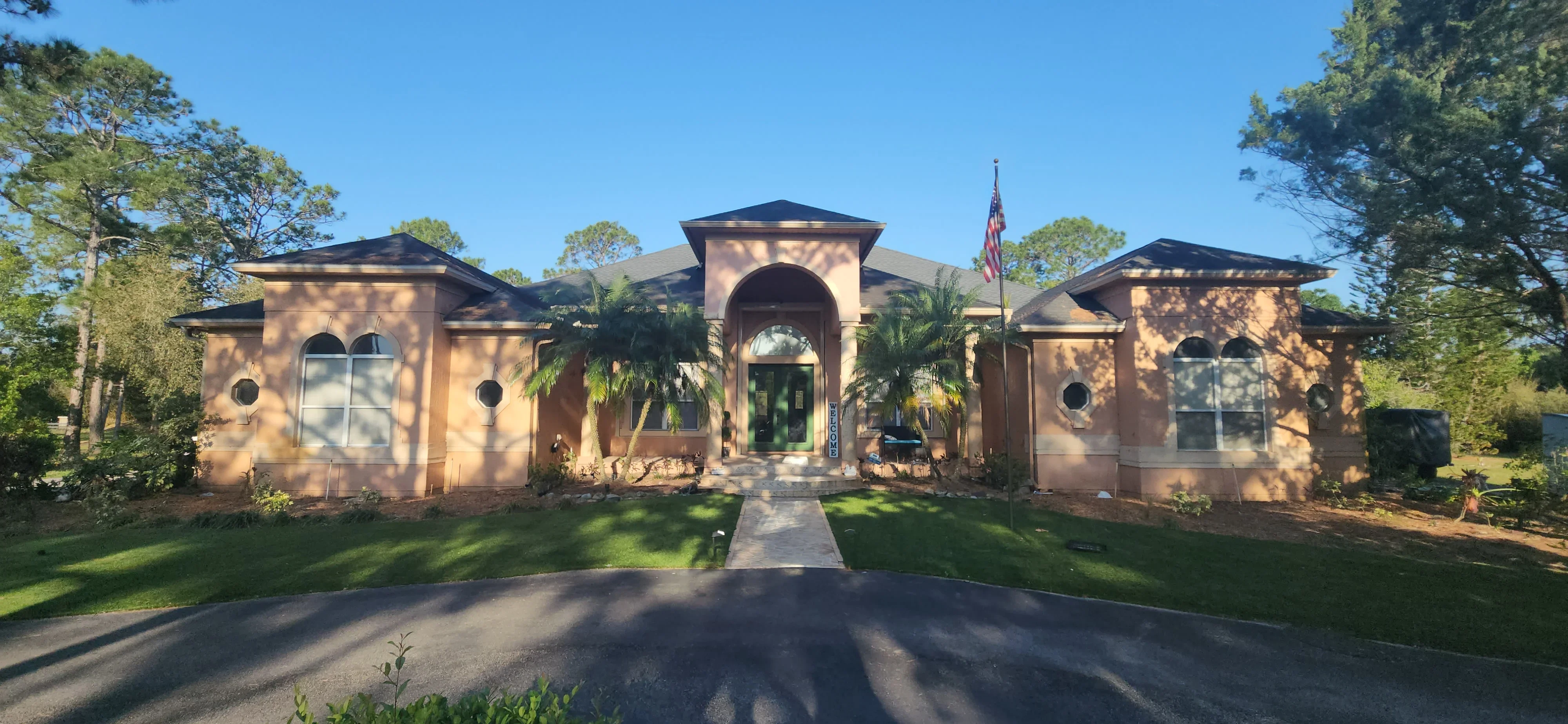 Brick and stucco residential home with arched entryway and palm trees, freshly painted exterior