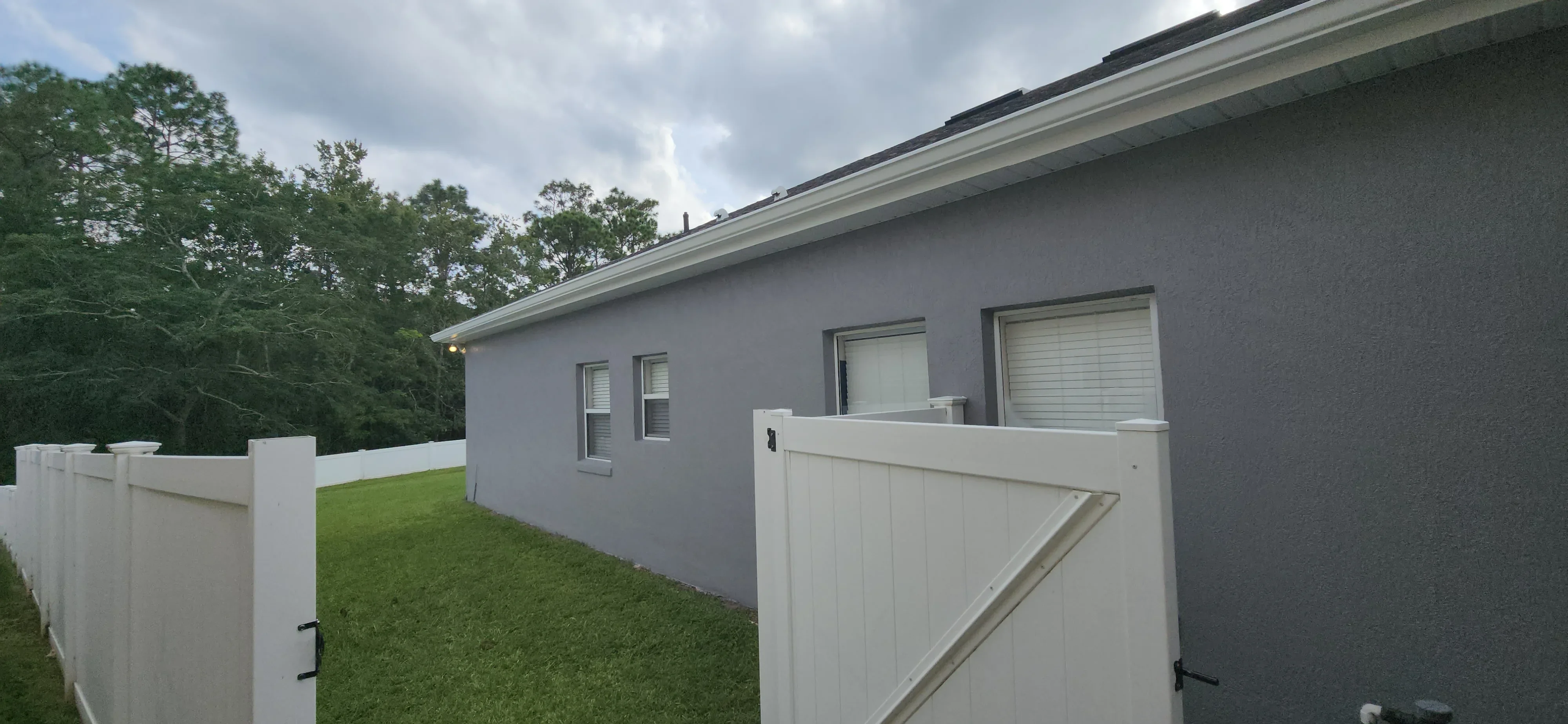 Gray painted house exterior with white trim, fascia, and vinyl fence