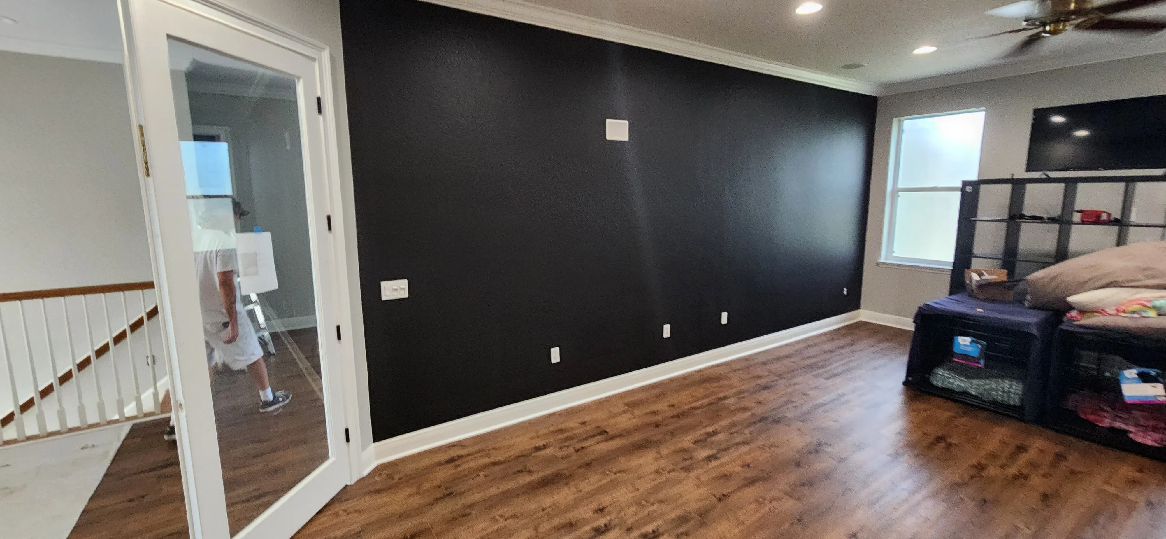 Charcoal accent wall with white trim and electrical outlets in bedroom with wood flooring
