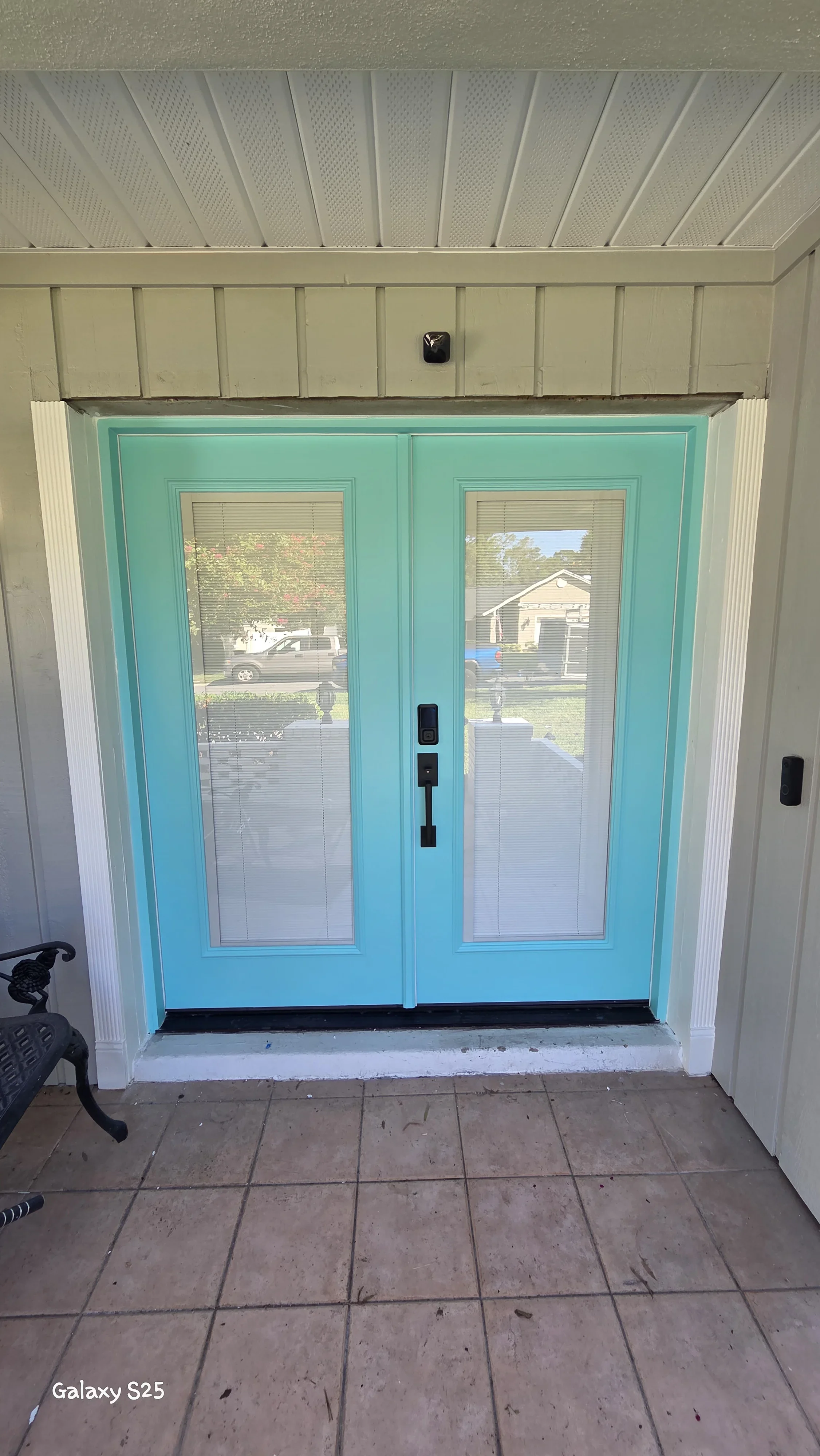 Turquoise painted double French doors with glass panels and white trim in covered entryway