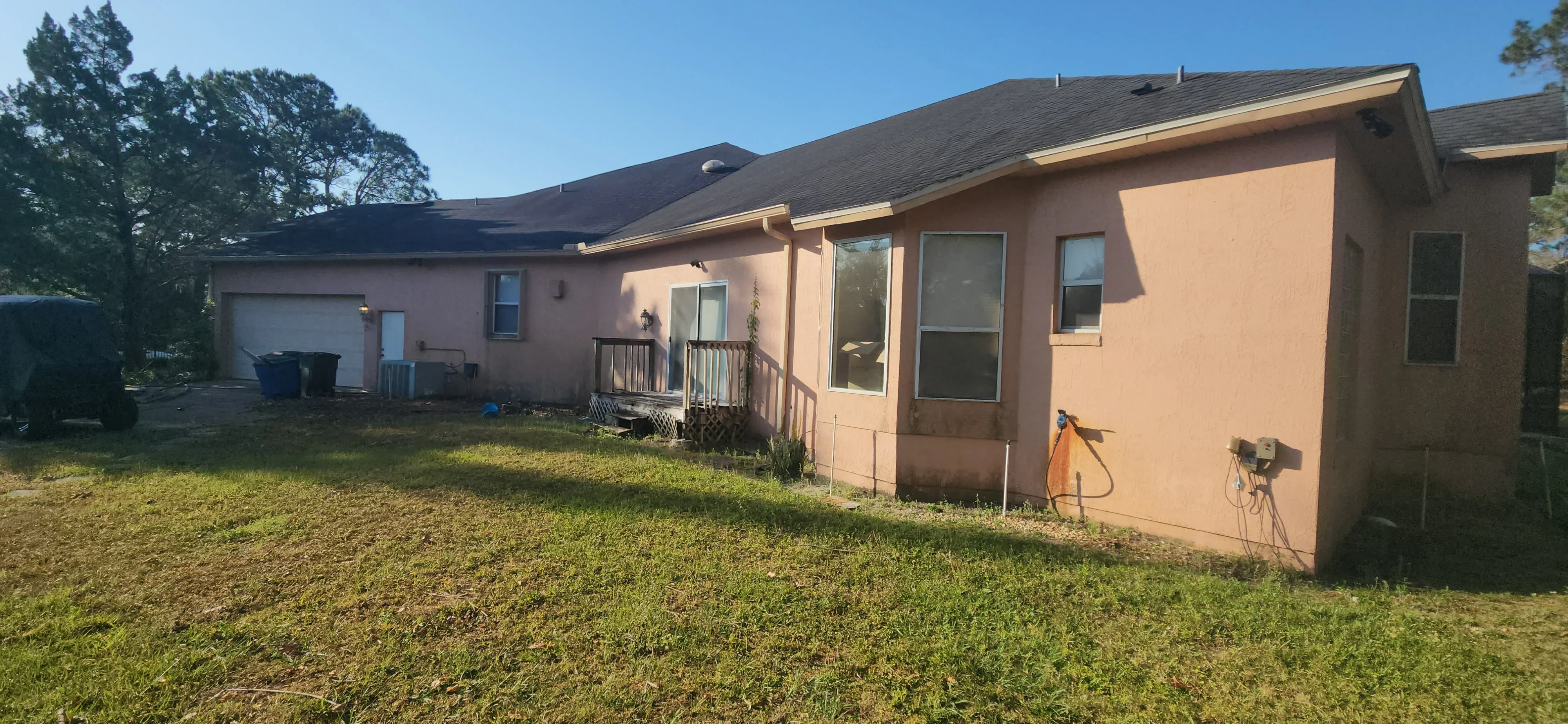 Exterior house with peach-colored stucco walls, dark roof, and metal railings on front porch